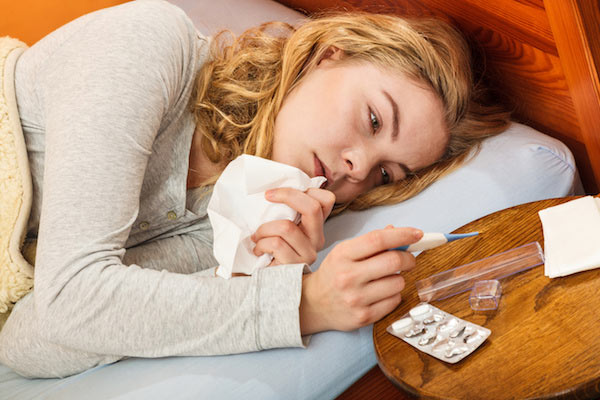 Mujer enferma de gripe consultando el termómetro