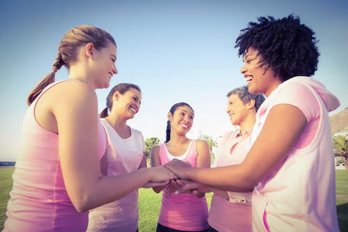 Mujeres en un círculo con ropa rosa contra el cáncer de mama