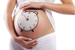 Mujer embarazada con un reloj pintado en la barriga